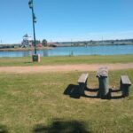 A bench sits in a grassy area overlooking a body of water, providing a peaceful spot for relaxation.