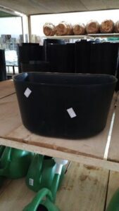A black bowl with two white stickers on it sits on a wooden table.