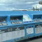 A blue trash can with a sign on it that says "Matthews Park Materials Recycling Center".