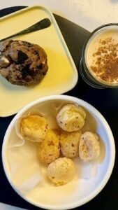 A bowl of pastries sits on a table next to a cup of coffee.
