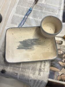 A bowl with a fish on it sits on a newspaper.