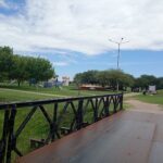 A bridge over a river with a park on the other side.