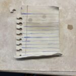 A broken piece of a spiral notebook sits on a table.