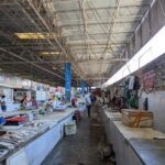 A busy market with people shopping and vendors selling.