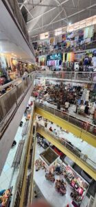 A busy marketplace with people shopping and walking around.