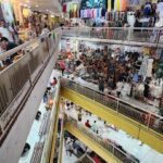 A busy marketplace with people shopping and walking around.