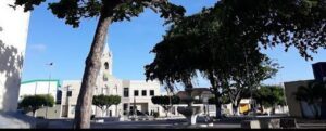 A church with a clock tower and a fountain in front of it.