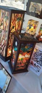 A collection of colorful glass lamps, including a lamp with a cactus design, are displayed on a table.