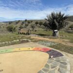 A colorful scale is set in a field with a bench nearby.