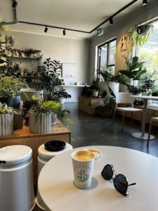 A cup of coffee sits on a table next to a pair of sunglasses.