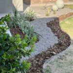 A garden pathway with a variety of plants and rocks.