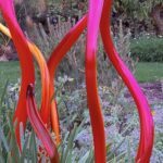 A garden with a variety of plants, including a red and yellow flower, and a red and orange plant.