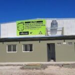 A green sign with white letters is posted on the side of a building.