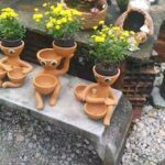 A group of ceramic figurines are sitting on a stone ledge, with some of them holding bowls.