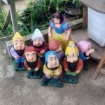 A group of garden gnomes are sitting on the ground.