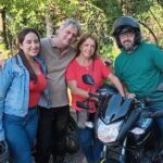 A group of people posing with a motorcycle, with one man wearing a helmet.