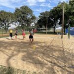 A group of women playing tennis on a sandy court.