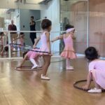 A group of young girls are practicing their dance moves in a room.