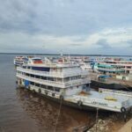 A large boat is docked at a pier, surrounded by other boats.