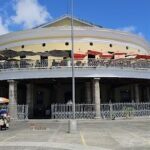 A large building with a yellow roof and a pole in the middle of the courtyard.