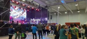 A large crowd of people are gathered in a room, enjoying a concert.