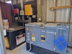 A large generator is sitting in a room with a yellow box and a black box.