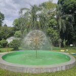 A large green fountain with a gold centerpiece and a water spout.