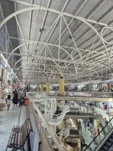 A large open mall with a white ceiling and a staircase leading to the upper level.