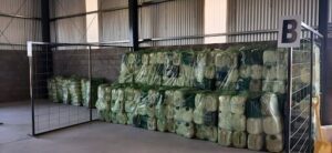 A large pile of green bags are stacked in a warehouse.