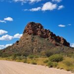 A large rock formation stands tall in the middle of a field.