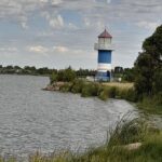 A lighthouse stands tall on a rocky shore, overlooking a body of water.