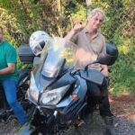 A man is sitting on a motorcycle, giving a thumbs up.
