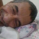 A man is smiling and laying down on a bed.