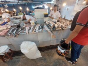 A man is standing in front of a table full of fish.