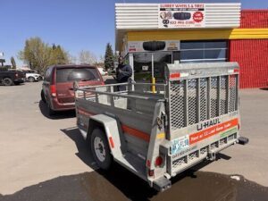A man is standing next to a truck that is parked in front of a tire shop.