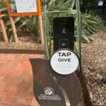 A man is taking a picture of a tap give sign.