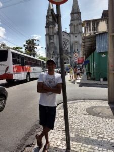 A man poses in front of a church with a street sign in the background.