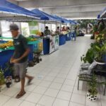 A man walks past a fruit stand with a variety of fruits on display.