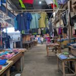 A market with a variety of clothing items hanging from the ceiling.