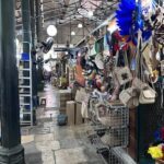 A market with a variety of items for sale, including handbags, hats, and other accessories.