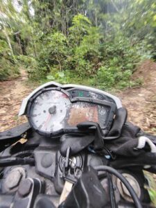 A motorcycle with a broken speedometer and a black glove on the handlebars.