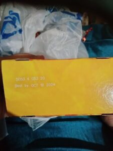 A person is holding a box with a yellow label on it.