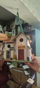 A person is holding a small house decoration that says "welcome" on it.