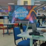 A person is working on a laptop in a room with a colorful sign on the wall.