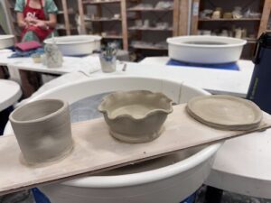 A person is working on a pottery wheel, creating a bowl.