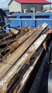 A pile of old wood is sitting on a blue trailer.