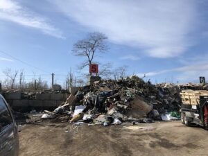 A pile of trash is sitting in a parking lot, with a sign nearby indicating the trash is for disposal.