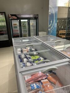 A refrigerator filled with food is open, revealing a variety of items such as frozen fries, milk, and other foods.