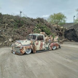 A rusty old truck is parked in a dirt lot.