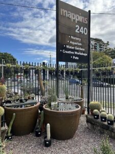 A sign for a nursery and aquarium is displayed in front of a fence.